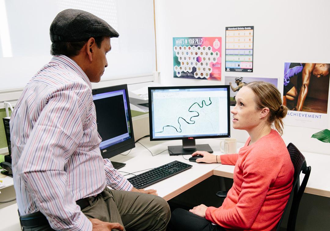 People having a discussion in front of a computer screen showing a map