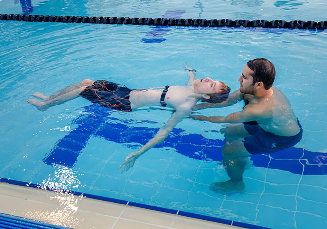 Trainer helping paralympic athlete in pool