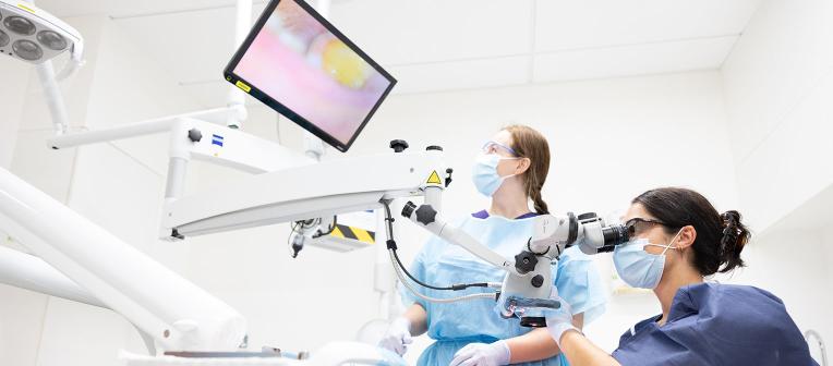 Two students examining a patient in the oral health clinic