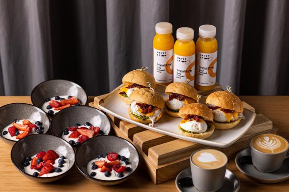 An assortment of food, including burgers, coffee and orange juice.