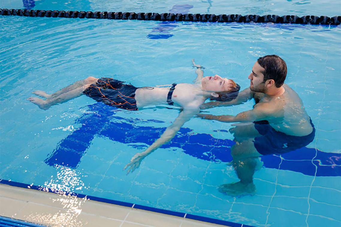 Trainer helping paralympic athlete in pool