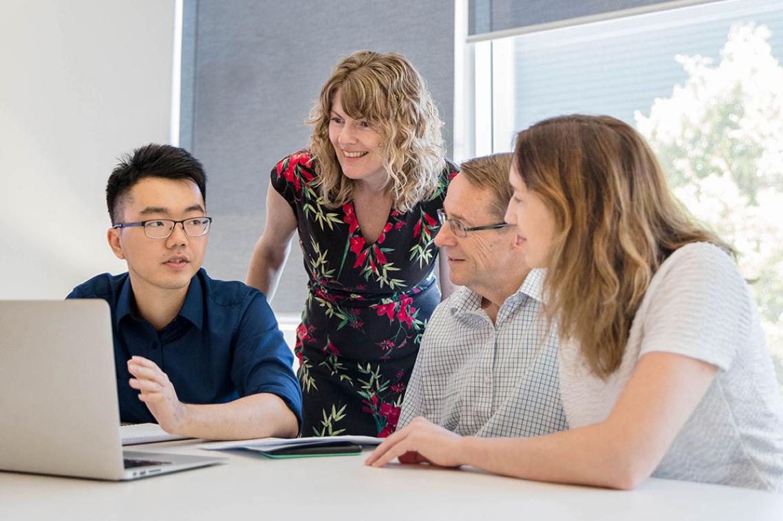 Four staff members sitting around a laptop