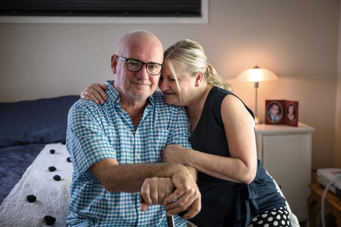 Mature couple embrace while sitting on the edge of a bed