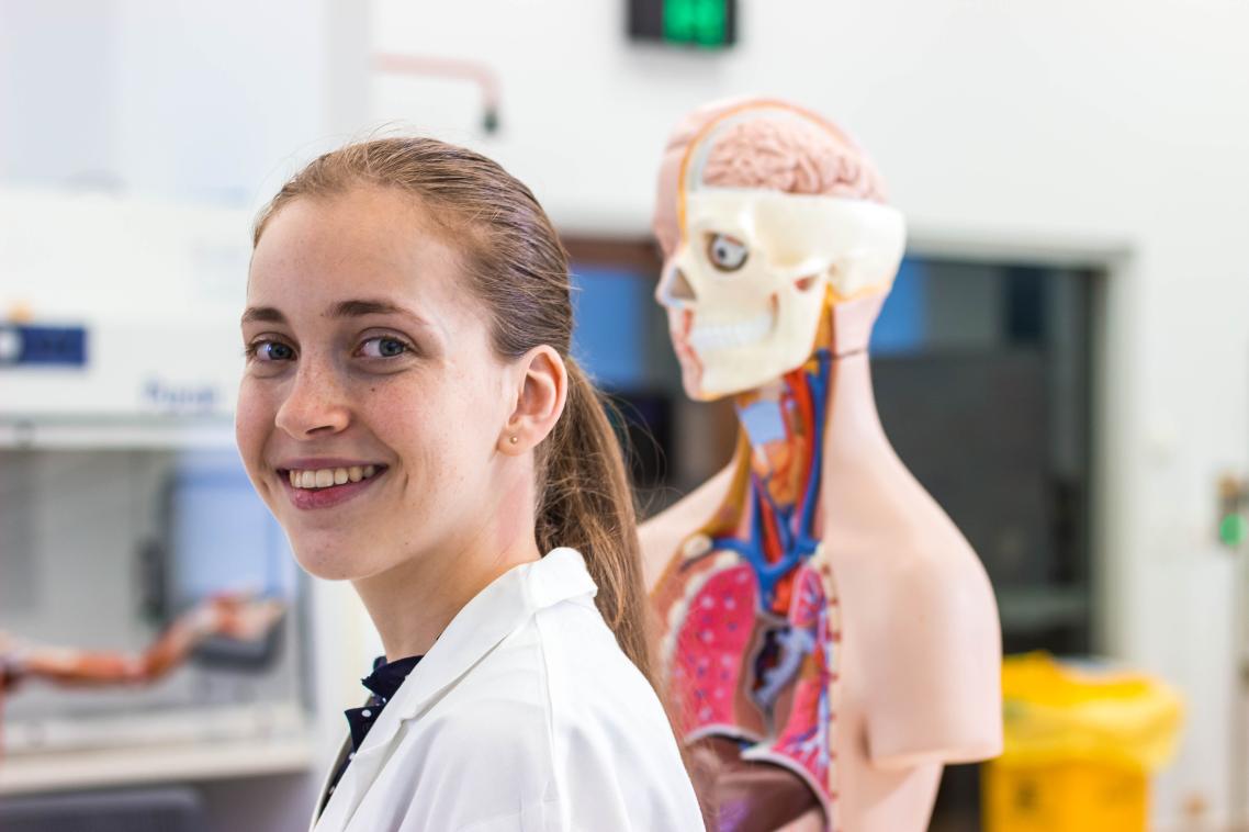 Biomedical student in lab coat and anatomic model 