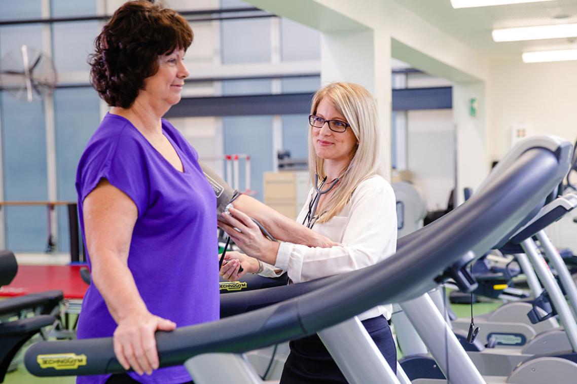 Women on treadmill is guided by an expert