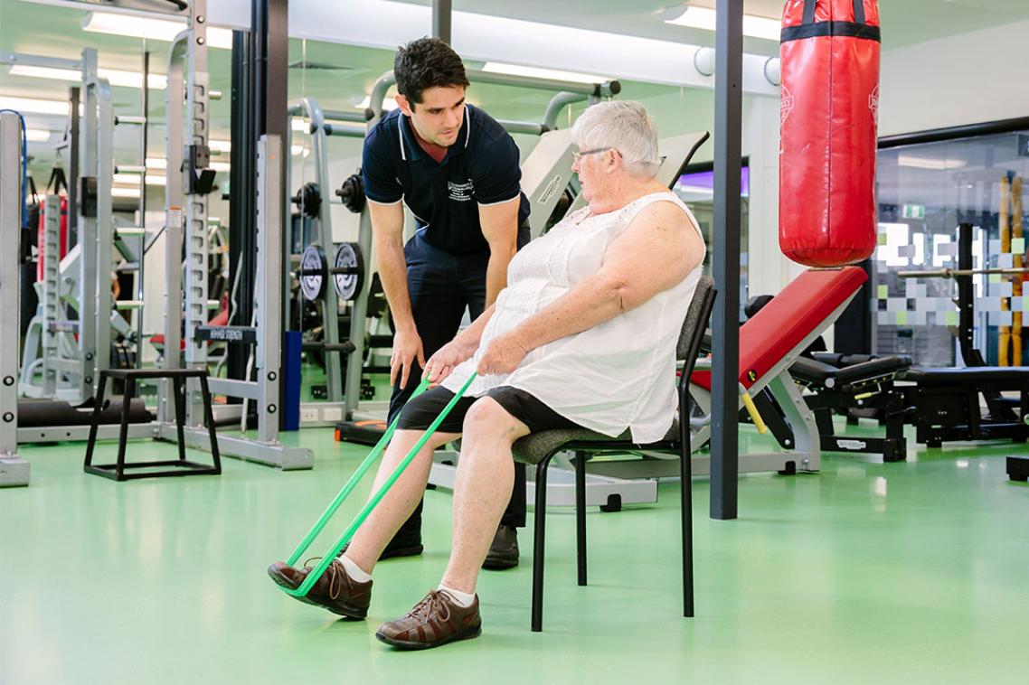 Woman in gym uses strap to stretch leg