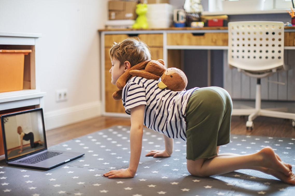 Child follows spinal stretching exercises on laptop