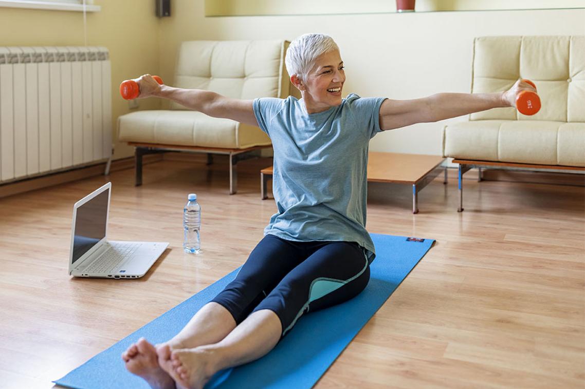 Woman on yoga mat lifting weights