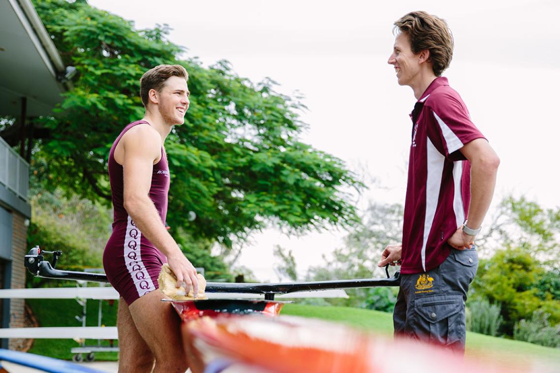 Two man standing near rowing equipment 