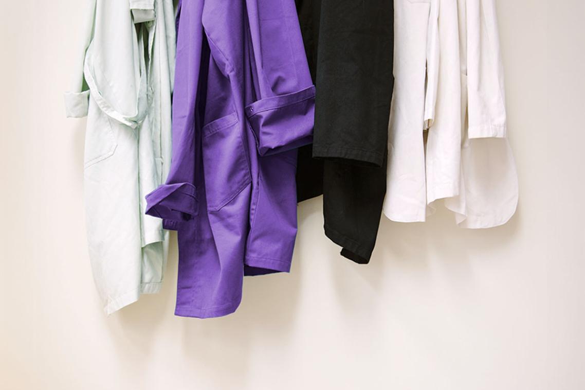 Coloured lab coats hanging on hooks