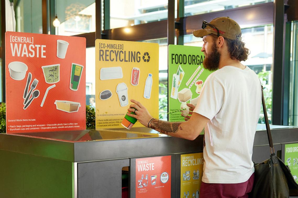 Student separating their rubbish into three different recycling bins