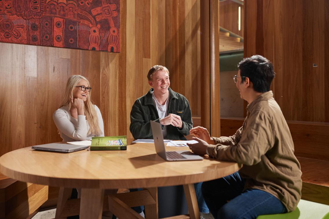 Three students sitting at a table and talking.